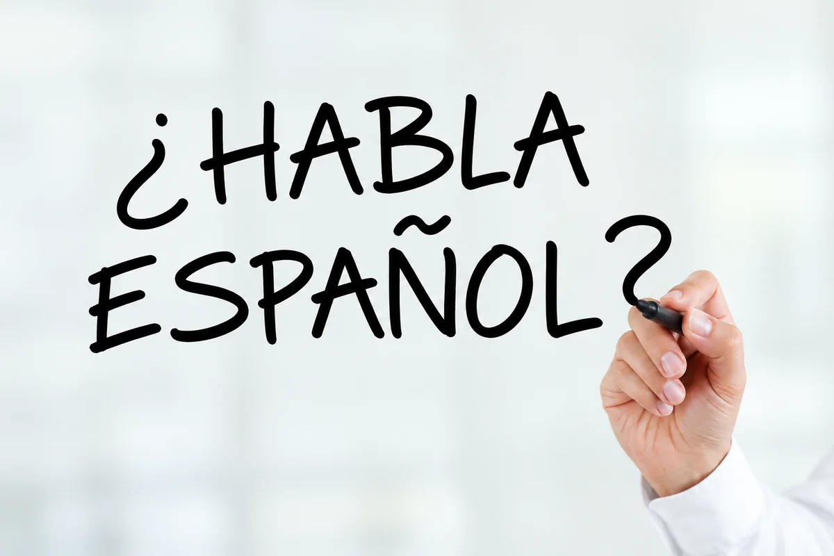 Hand writing “¿Habla español?” on glass